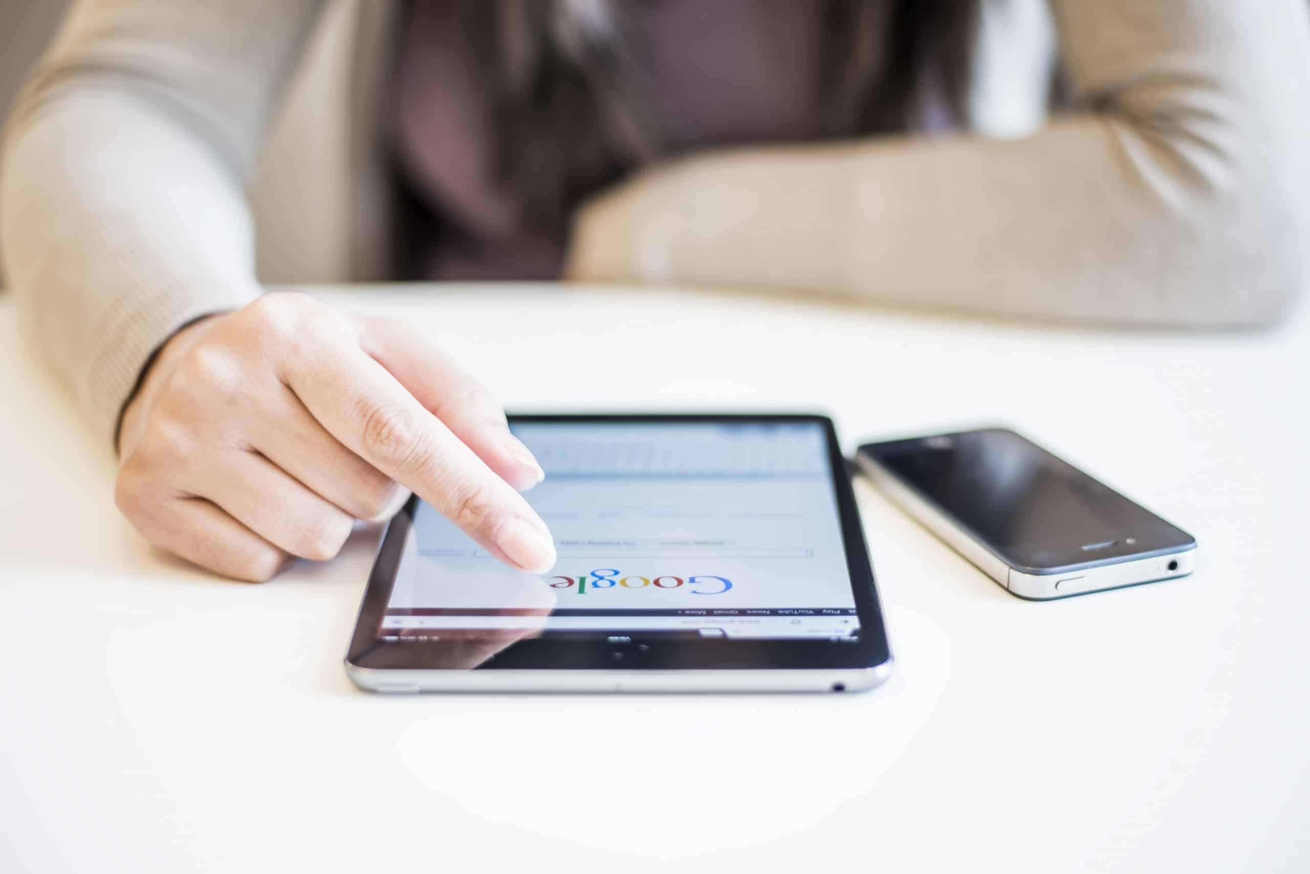Woman hands holding and touching on Apple iPad mini with Google search web page on a screen.